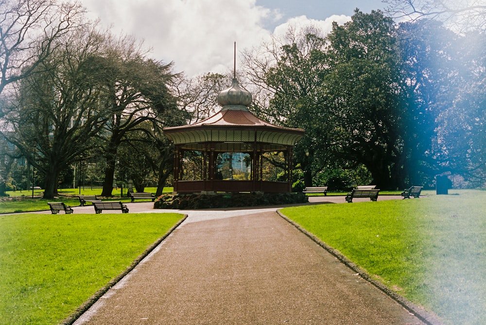 brown and white gazebo surrounded by green trees under blue sky during daytime